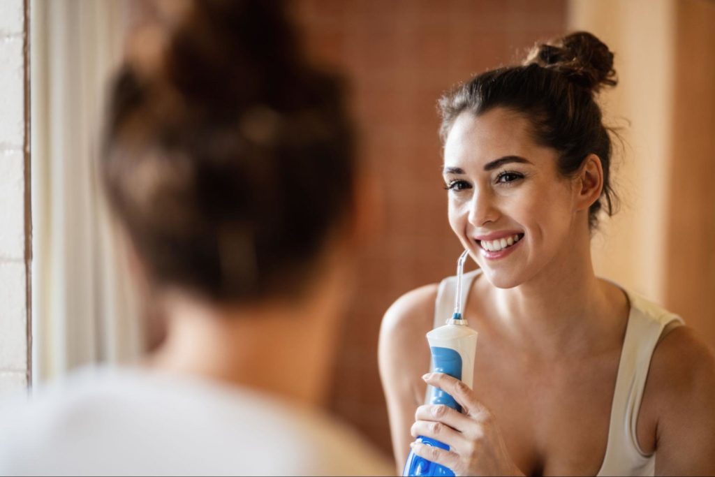 Woman using a water floss in the mirror